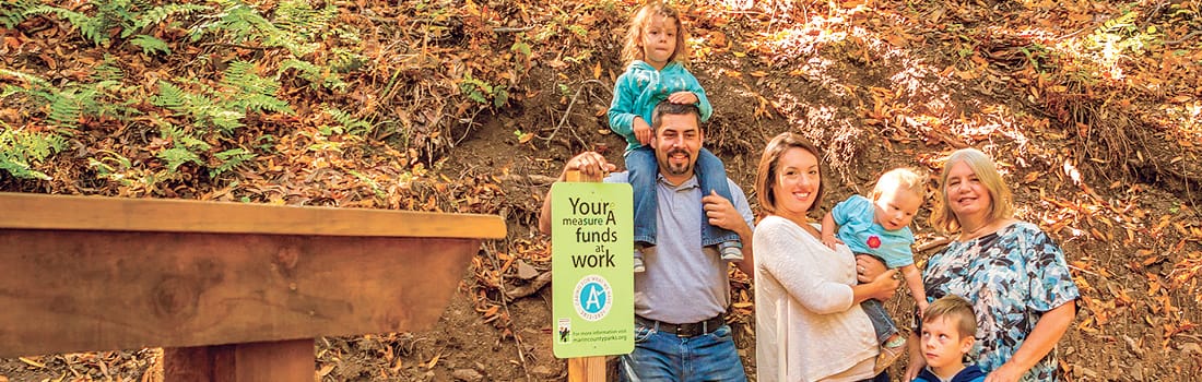 Family standing next to Measure A sign in Loma Alta Preserve