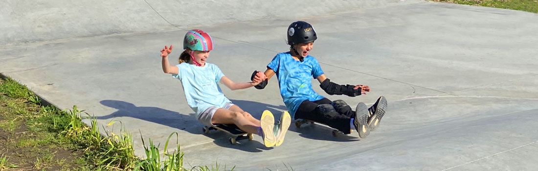 Students on skateboards holding hands at Valley Skatepark